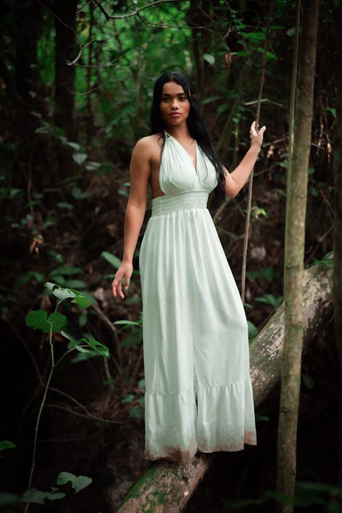 Beautiful Woman in White Dress Standing on Tree Trunk
