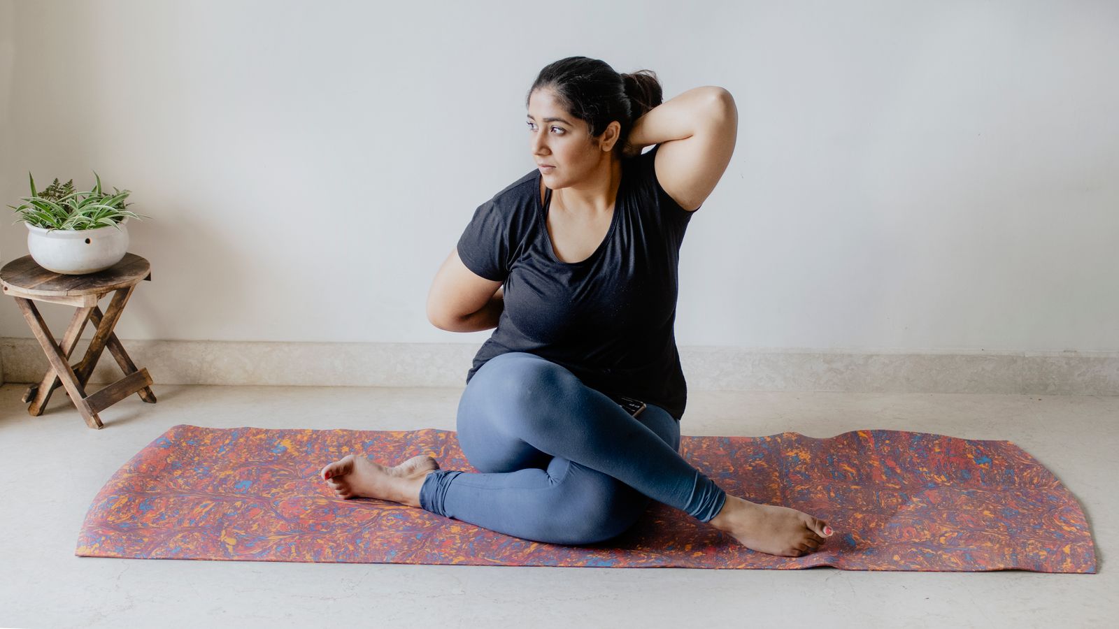 Woman practicing a seated yoga neck stretch pose indoors to relieve tension