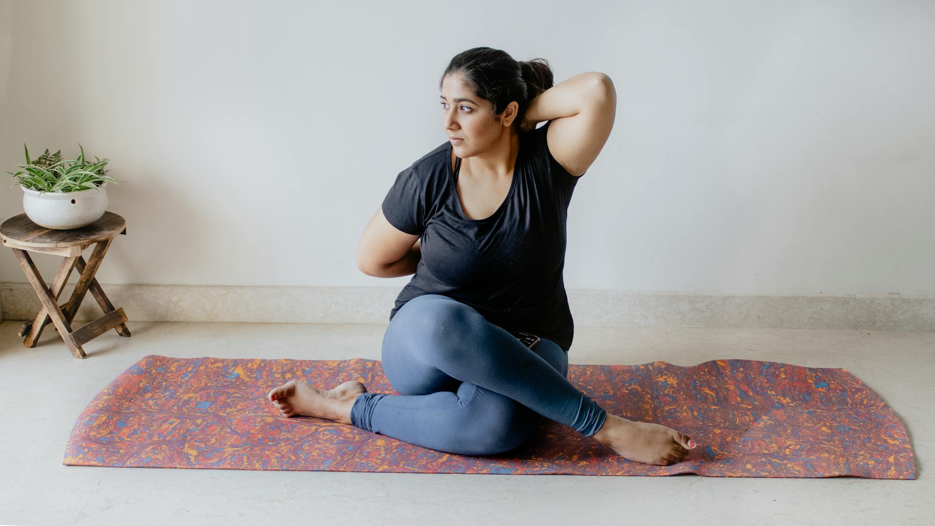 Indian woman practicing a seated yoga pose indoors, enhancing flexibility and mindfulness.