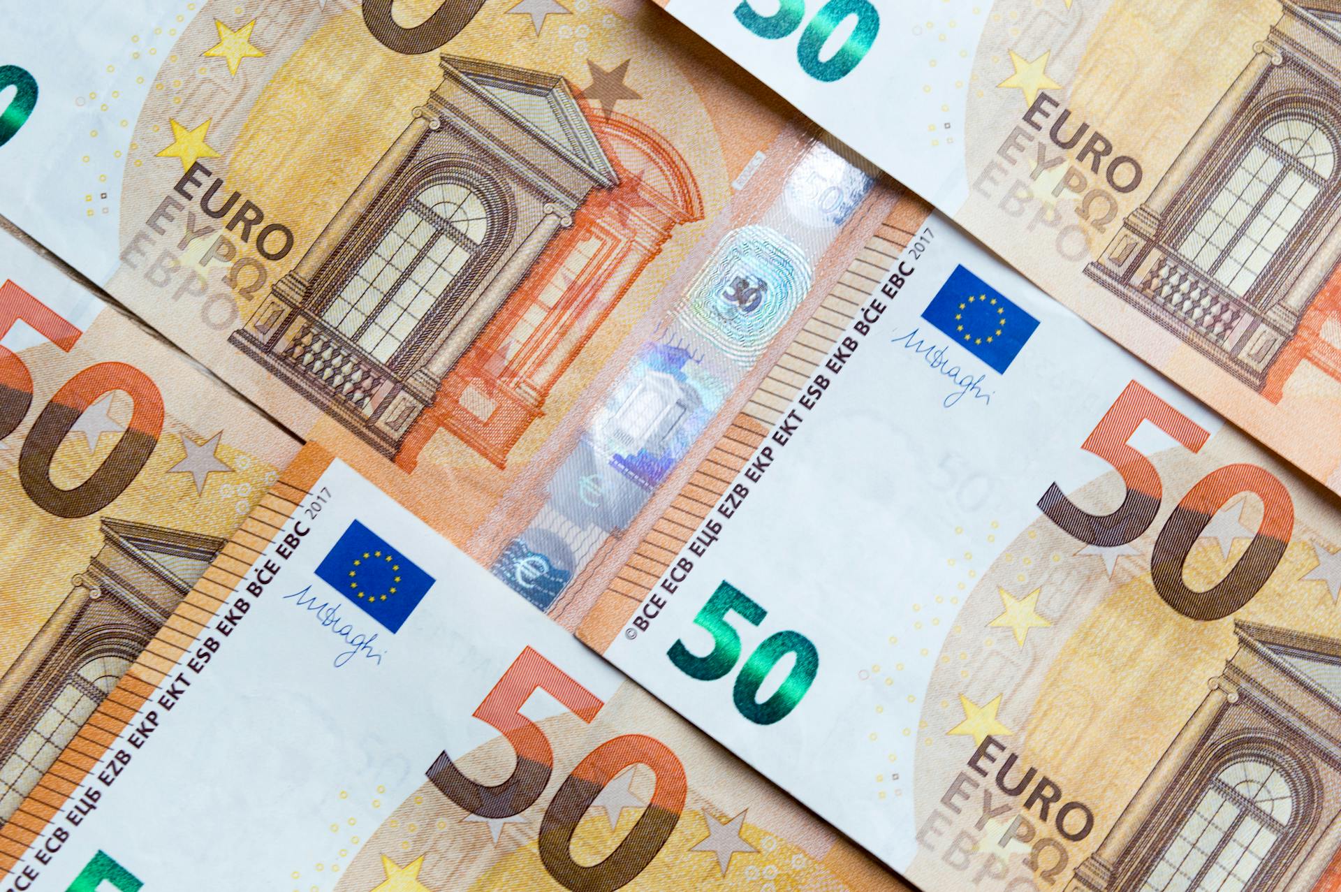 Detailed close-up of multiple overlapping euro banknotes depicting currency and finance themes.