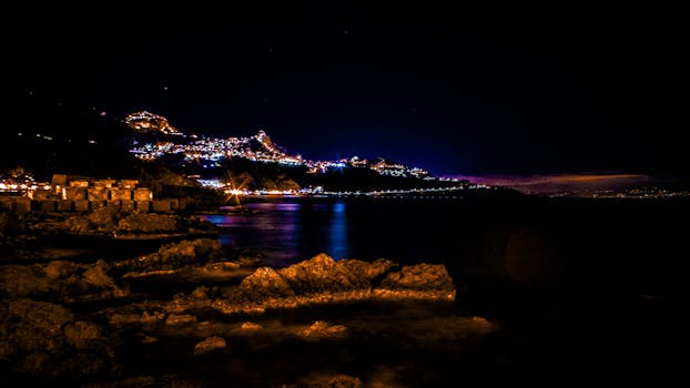 陶尔米纳海岸线的夜间景观令人惊叹，城市灯光倒映在大海中