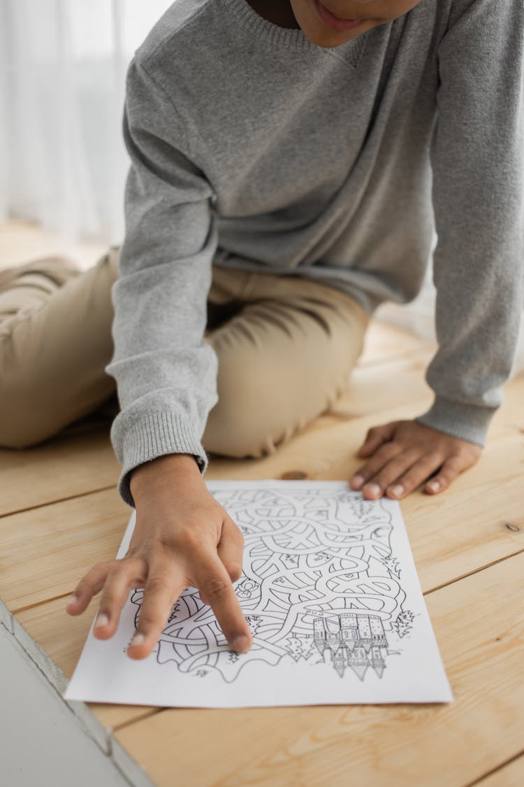 Unrecognizable Black Child Solving Painted Maze On Floor At Home