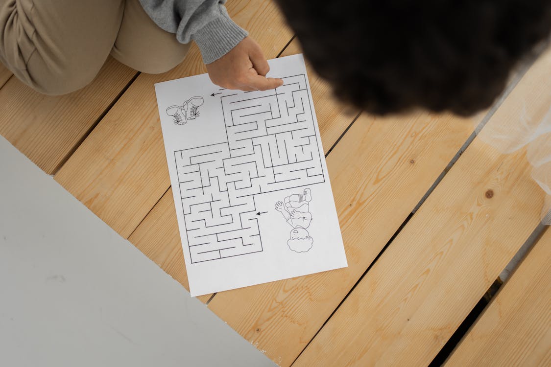 Free Unrecognizable child solving labyrinth test printed on paper at home Stock Photo