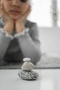 Pensive little ethnic girl lying on floor and looking at stones stack