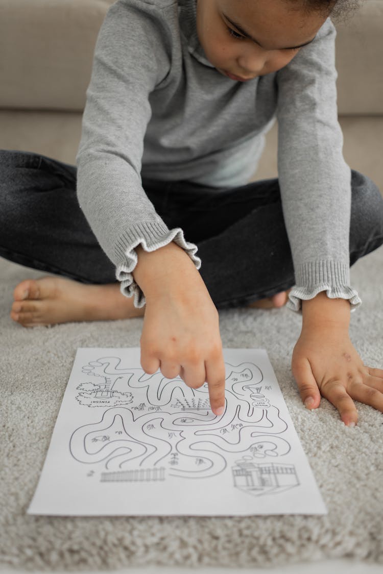 Serious Little African American Child Solving Labyrinth Test On Floor