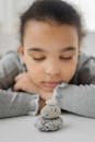 Peaceful little ethnic girl sleeping on floor near stones stack