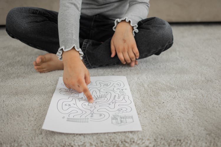 Faceless Kid Sitting On Rug And Passing Painted Labyrinth