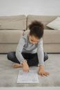 Concentrated black kid sitting on floor and and solving logical exercise