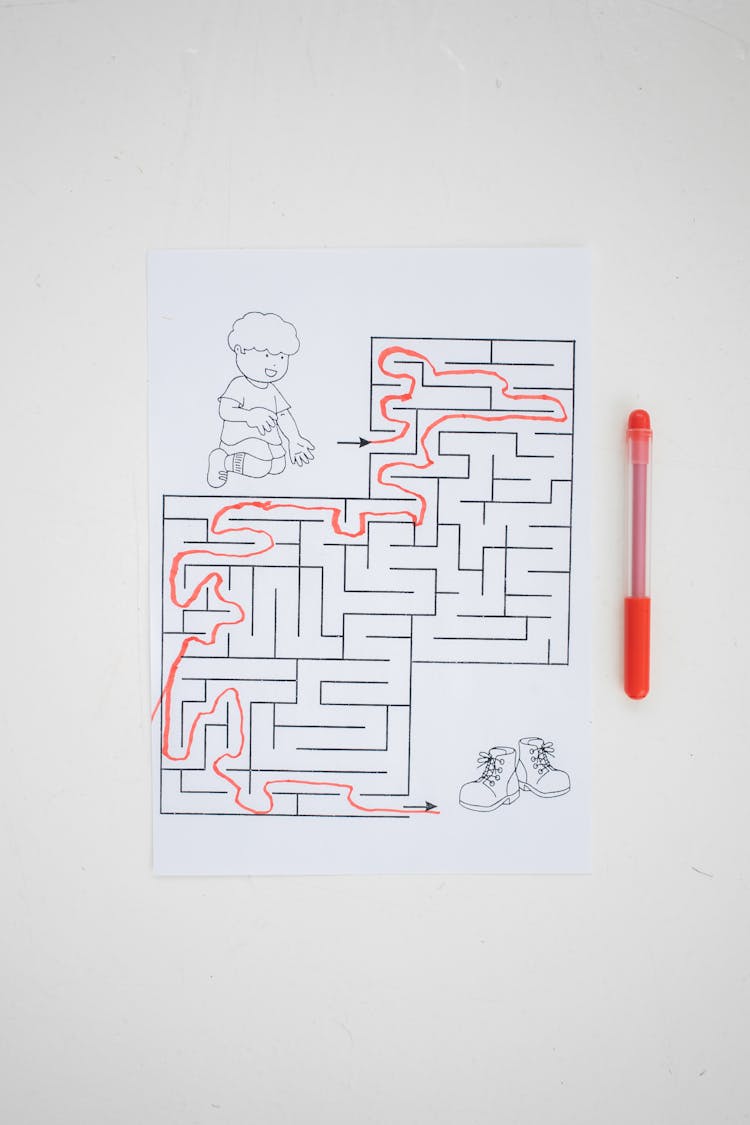 Kids Worksheet With Solved Maze Placed On Table With Pen