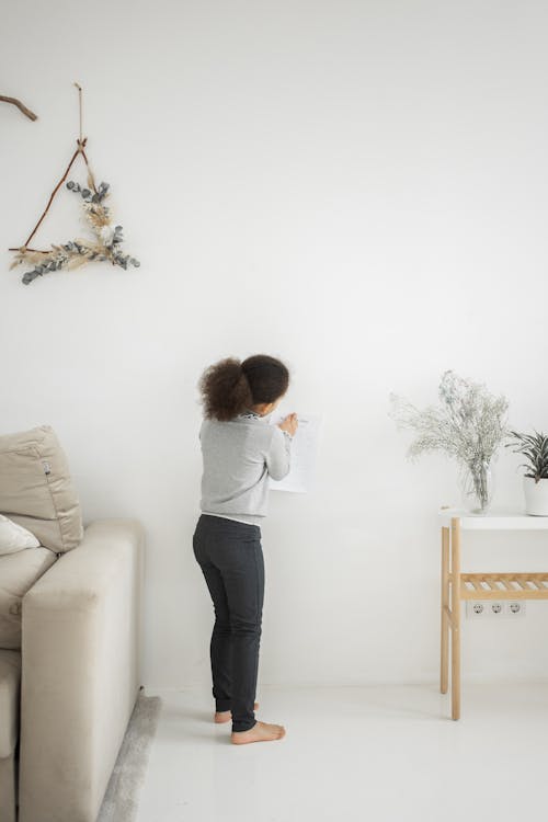 Anonymous black girl attaching paper on wall