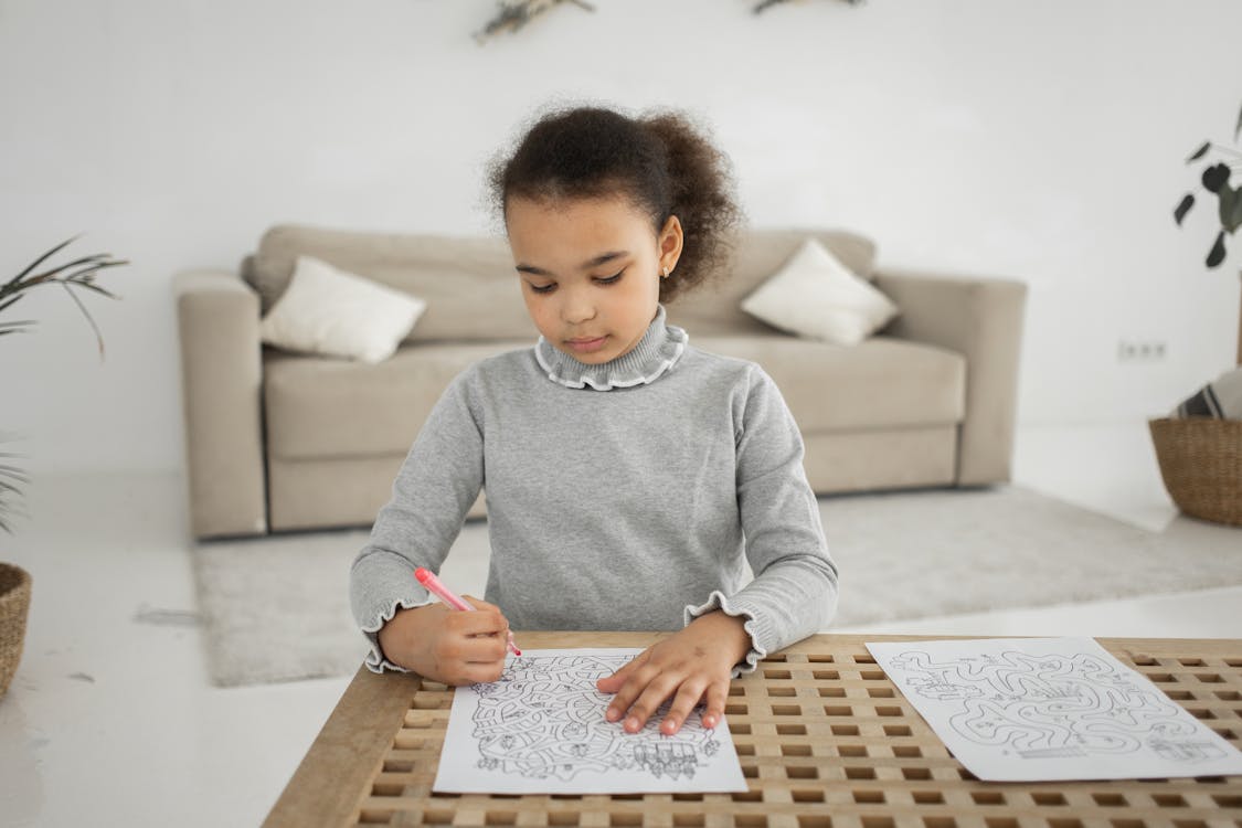 Focused ethnic girl drawing on paper