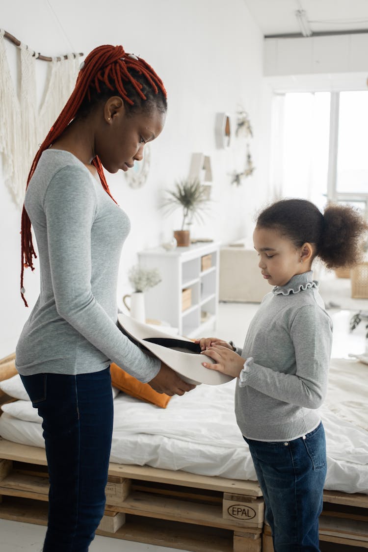 Black Woman And Girl Looking At Hat