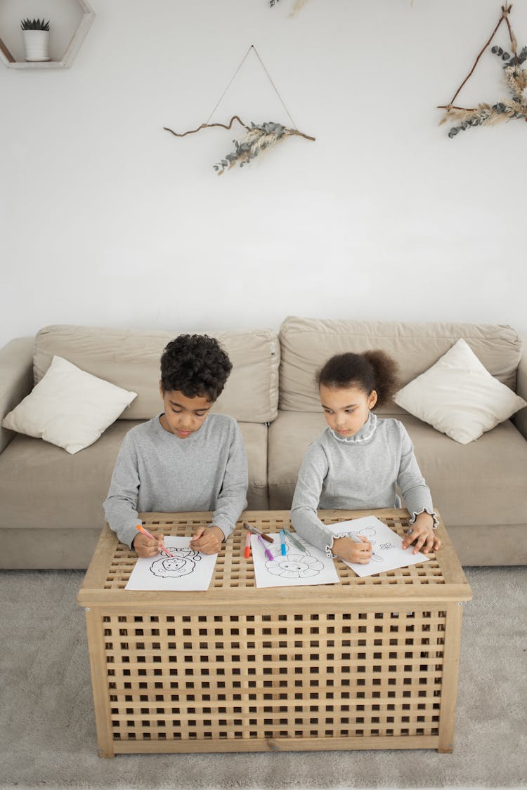 Children Sitting At Table And Coloring Pictures