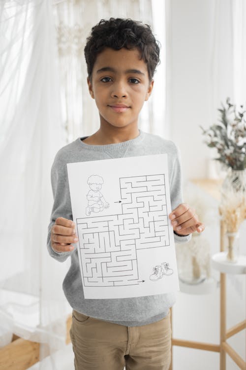 Cute boy showing paper with labyrinth