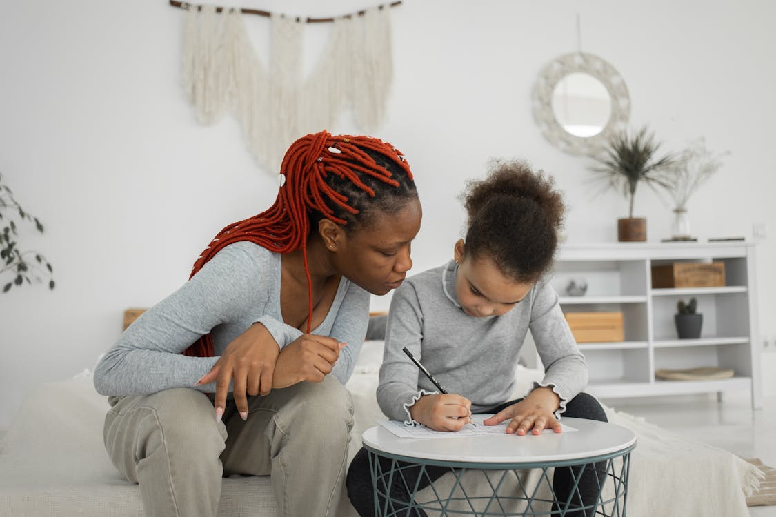 Free Black woman and girl doing task at table Stock Photo