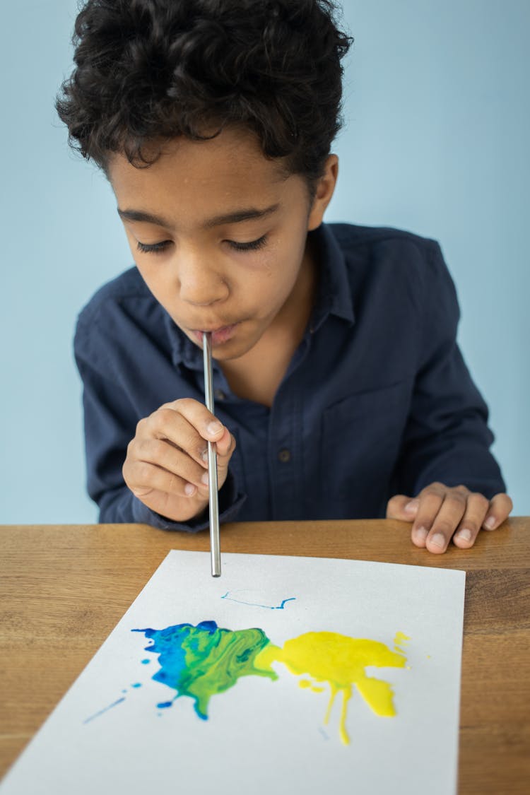 Ethnic Boy Blowing Paint With Straw