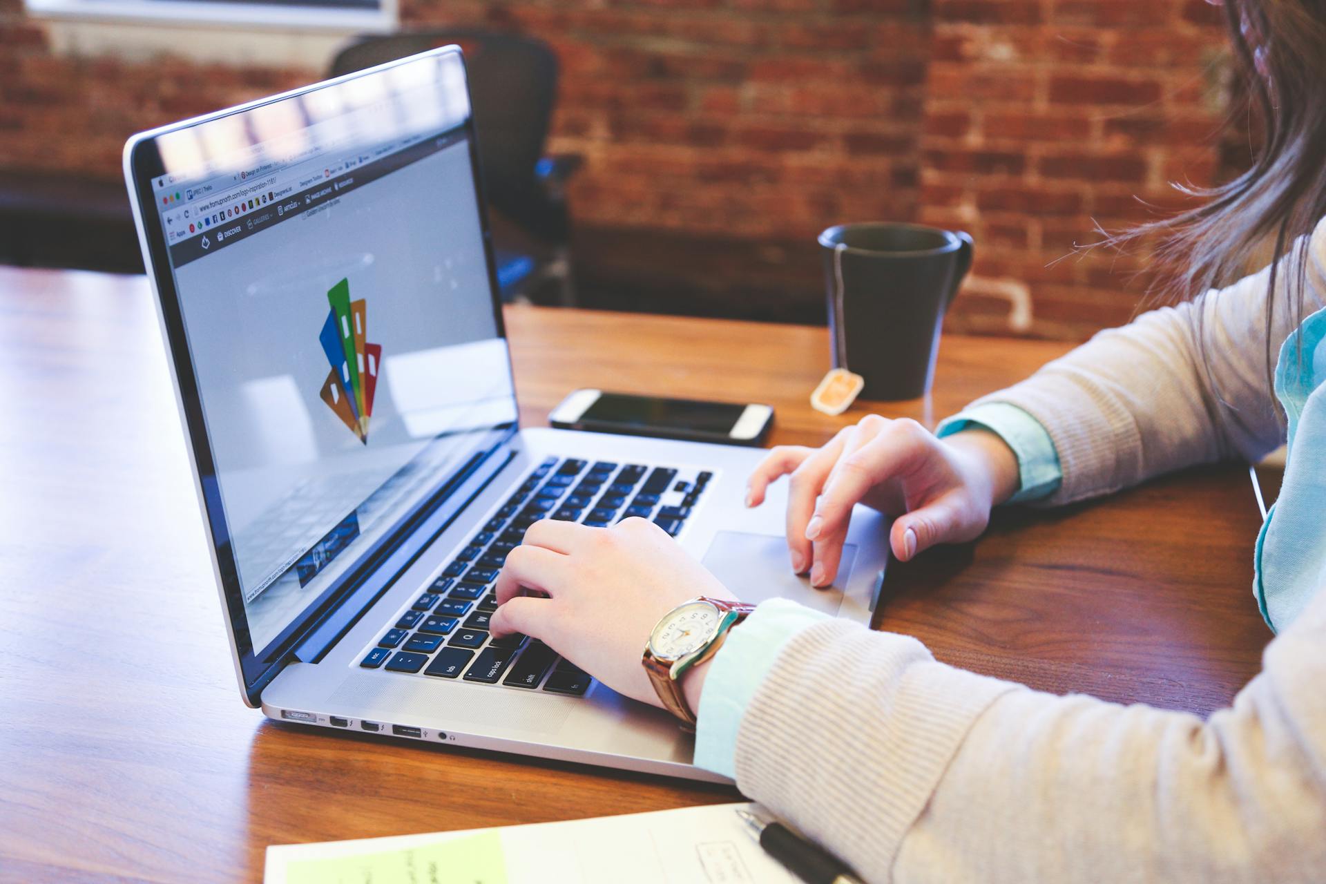 Woman working on design project using laptop at modern workspace indoors.