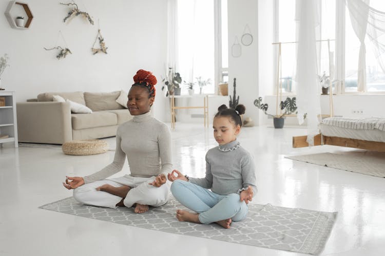 Cute Ethnic Kid With Mom Meditating With Closed Eyes In Lotus Pose