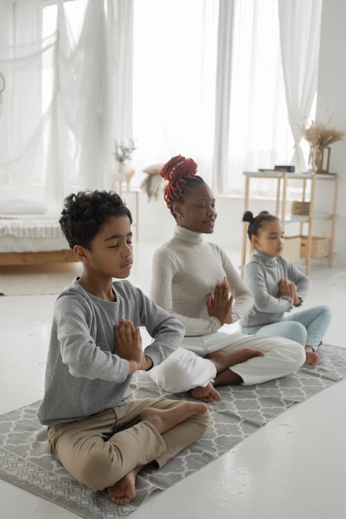 Free Cute ethnic children with young mom meditating together with closed eyes at home Stock Photo