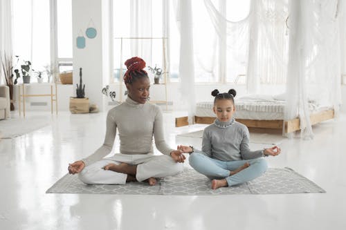 Free Young black mother practicing yoga with daughter in light bedroom Stock Photo