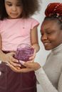 Happy ethnic mother and little daughter playing with shiny slime