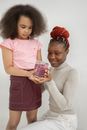 Cute black kid showing jar with handmade slime to mom