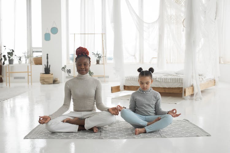 Adorable African American Kid With Young Mom Practicing Yoga In Lotus Pose