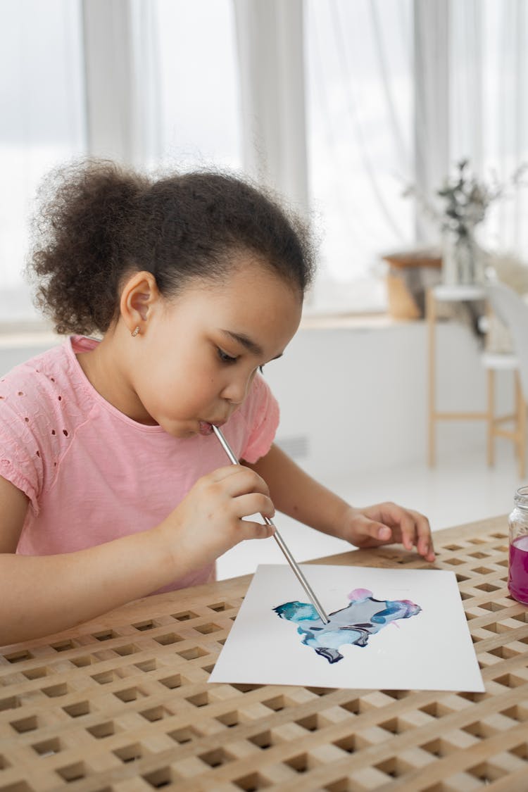 Focused Ethnic Kid Painting On Paper With Straw Using Blowing Technique