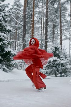 Beautiful figure skater in a red dress glides gracefully on a snowy forest pond.