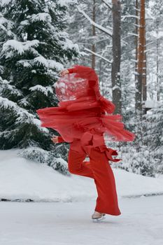 Dynamic image of a figure skater in red twirling on ice amidst a snowy forest. Captivating winter scene.