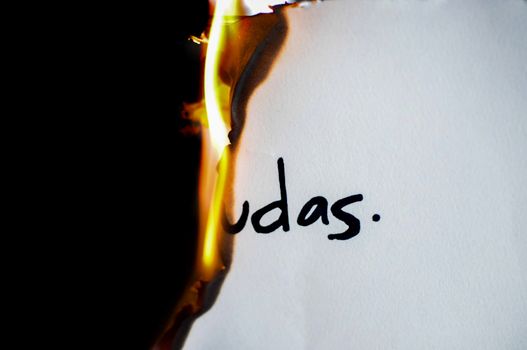 A piece of paper with handwritten text 'udas' partially engulfed in flames.