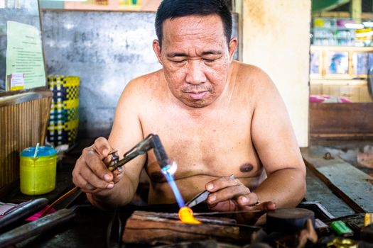 A Shirtless Man Holding a Blow Torch