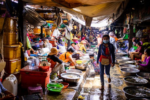 A lively wet market scene with vendors selling fresh seafood and a woman wearing a facemask.