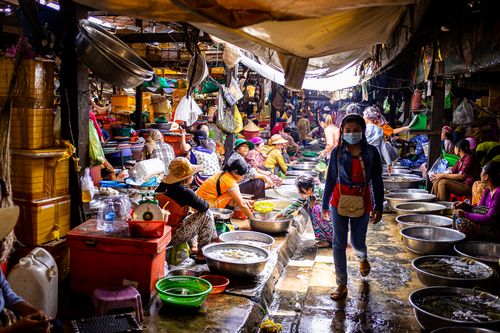 Free A lively wet market scene with vendors selling fresh seafood and a woman wearing a facemask. Stock Photo