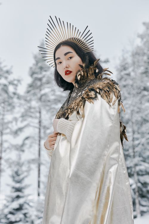 Free Portrait of a woman in a white dress and feathered cape in a snowy forest. Stock Photo