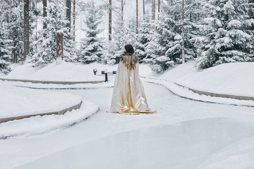 Free A person in a regal cape stands amidst a snowy forest, creating a whimsical winter scene. Stock Photo