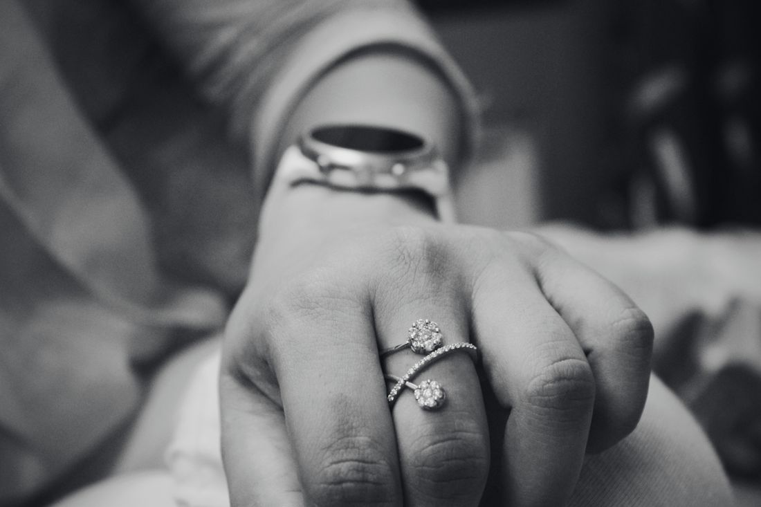 Hands wearing a diamond ring, black and white