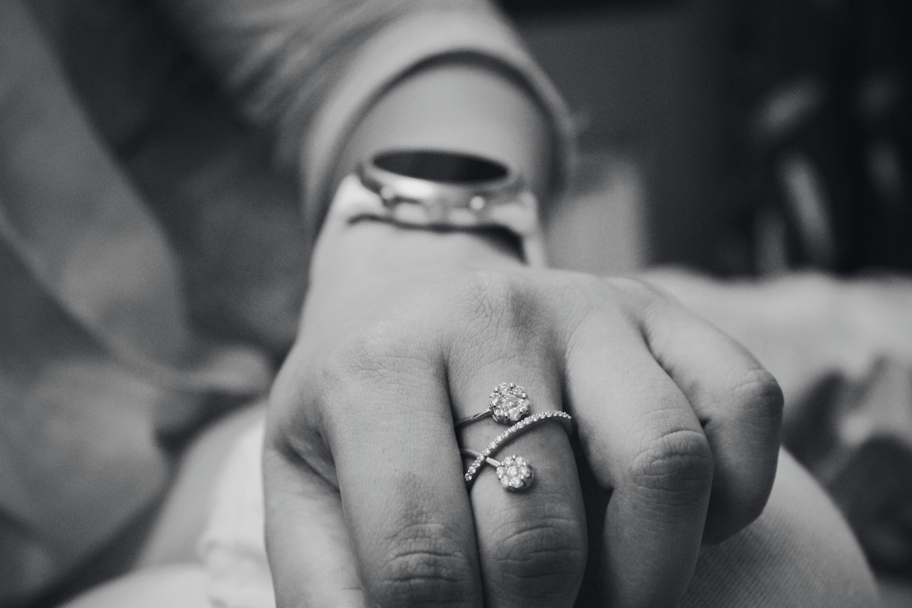 Hands wearing a diamond ring, black and white