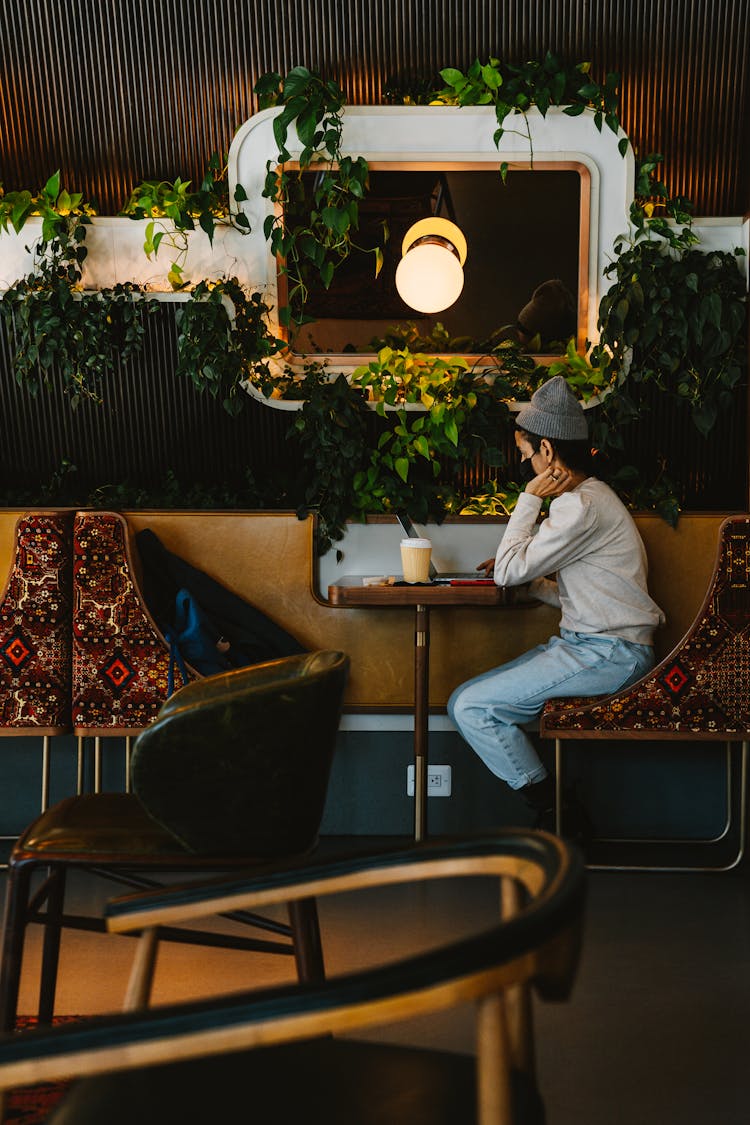 Person Wearing Long Sleeve Top And Beanie Sitting On A Bar Stool