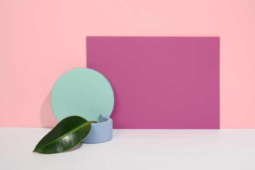 A minimalist abstract composition with geometric shapes and a green leaf on a pastel background.