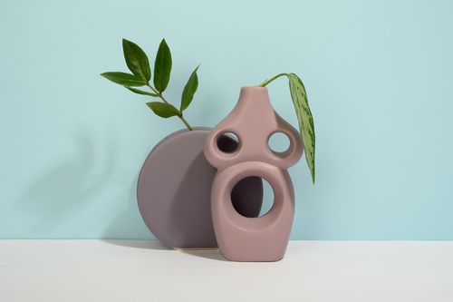 Free Stylish vases with green leaves on a soft light blue background, perfect for minimalist decor. Stock Photo