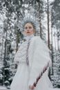 Woman in White Dress and Headdress Standing Near Brown Trees