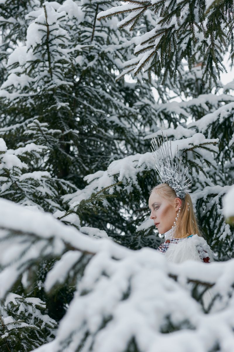 Elegant woman with crown and fur coat in snowy forest