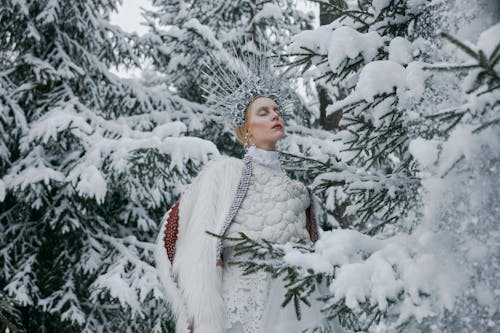 Woman Wearing a Crown Standing Near Snow Covered Trees