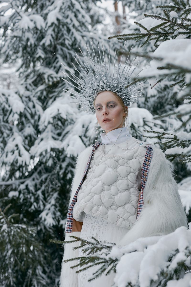 Woman in white dress with fur coat in winter forest