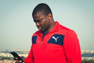 Man in Red Zip Jacket Using a Smartphone