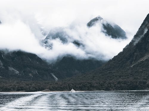 Photography of Body of Water Surrounded by Mountains and Fogs