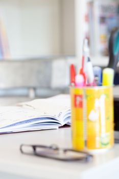 Blurred journal, eyeglasses, and colorful stationery on a tidy desk.