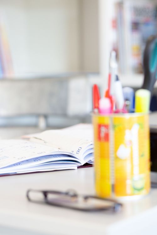 Free Blurred journal, eyeglasses, and colorful stationery on a tidy desk. Stock Photo