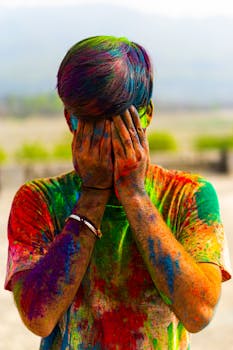 A person covered in colorful powders celebrating the vibrant Holi festival outdoors.